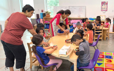 Teachers guiding preschoolers through a hands-on activity table