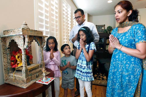 A family offering prayers together at their home mandir