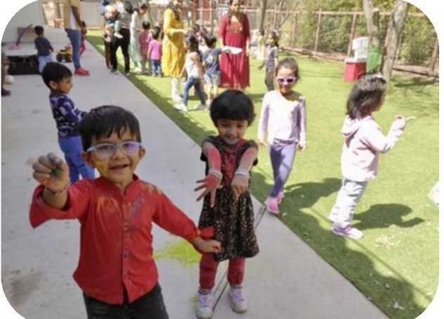 Young Aum School students playing outdoors during a Holi celebration