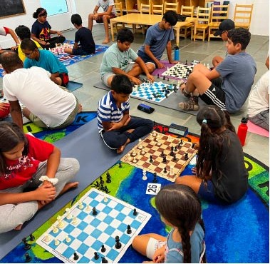 Summer camp chess club playing matches together on the floor